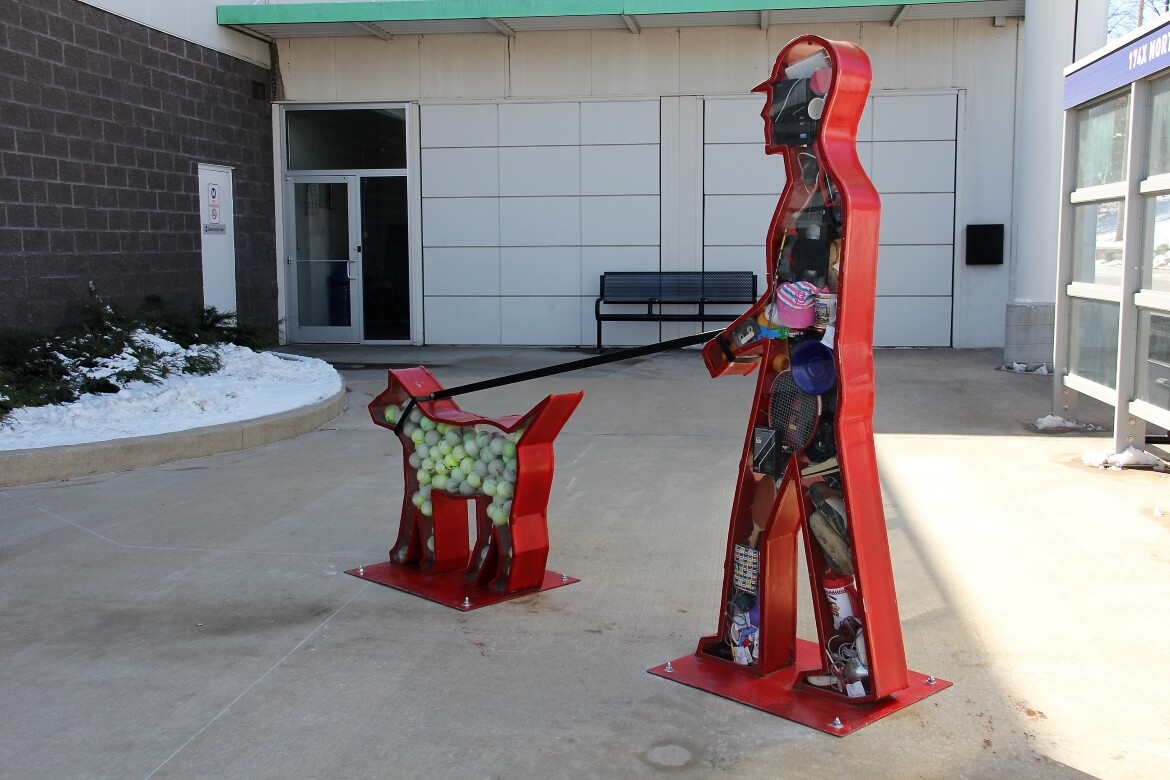 I Want was created by artist Victoria Fuller and is currently installed at the North County Transit Center. The silhouetted figures of a man walking his dog are filled with everyday consumer objects.